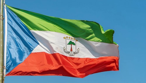 The flag of Equatorial Guinea flutters in the wind, isolated against a blue sky
