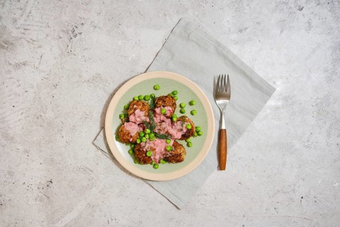 Top view of meatballs with fresh green peas and cranberry sauce on grey stone background