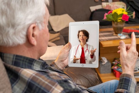 Symbolic image of telemedicine, elderly patient speaking to a doctor in a video conference from