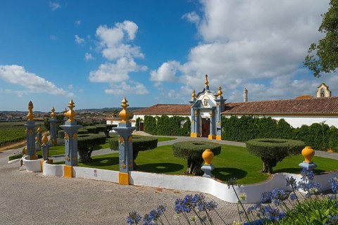 Traditional building in a well-kept garden with hedges and decorative elements under a sky with