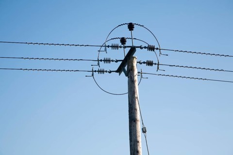 Close up of electricity cables and telegraph pole against blue sky, UK
