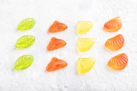 Various fruit jelly candies on gray concrete background. side view, close up