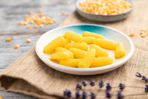Jelly corn candies on gray wooden background and linen textile. close up, side view, selective