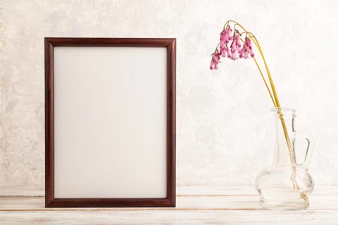 Wooden frame with pink dicentra, broken heart in glass on gray concrete background. side view, copy