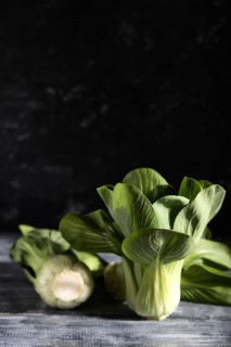 Fresh green bok choy or pac choi chinese cabbage on a gray wooden background. Hard light, contrast,