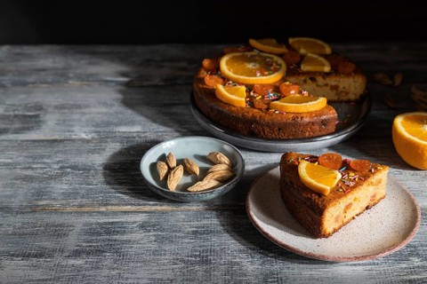 Orange cake on a gray wooden background. Hard light. contrast, low key. Side view, copy space