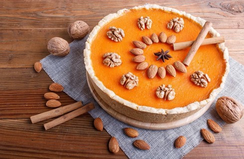 Traditional american sweet pumpkin pie decorated with nuts, on brown wooden background. close up,