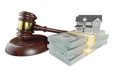 Miniature house with stack of money and wooden gavel isolated on a white background