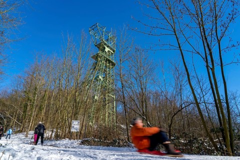 Winter in the Ruhr area, toboggan run on a forest path at Lake Baldeney, headframe of the former