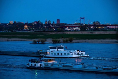 Cargo ship on the Rhine near Duisburg-Beeckerwerth, skyline of the city centre, with town hall,