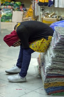Tired sales assistant in a textile shop in the historic centre of Genoa, Italy, Europe