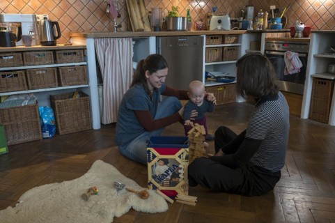 Young mother with her sister and with her son, 8 months, playing on the parquet floor,