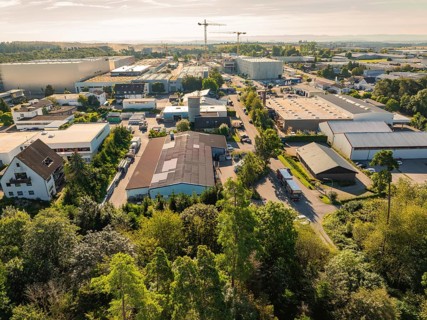 Industrial area with various buildings and a crane in the background, trees along the streets,