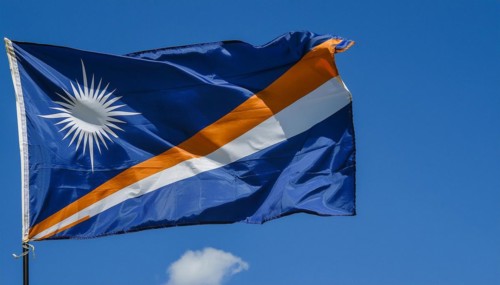 The flag of the Marshall Islands, Pacific Islands, flutters in the wind, isolated against a blue