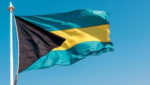 The flag of the Bahamas flutters in the wind, isolated against a blue sky