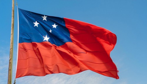 The flag of Samoa, fluttering in the wind, isolated against a blue sky