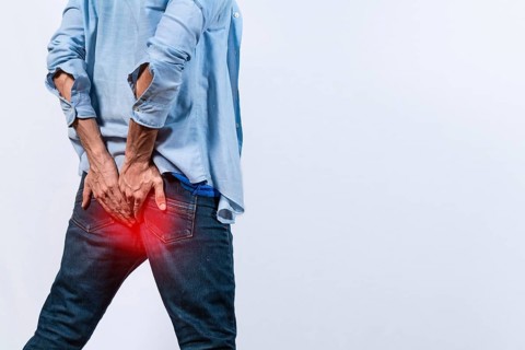 Man with digestive problem touching his buttock, man with hemorrhoid problem on isolated