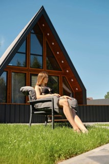 Young woman sunbathing on the lawn of a modern tiny house