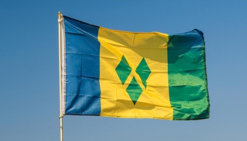 The flag of the Grenadines flutters in the wind, isolated against a blue sky