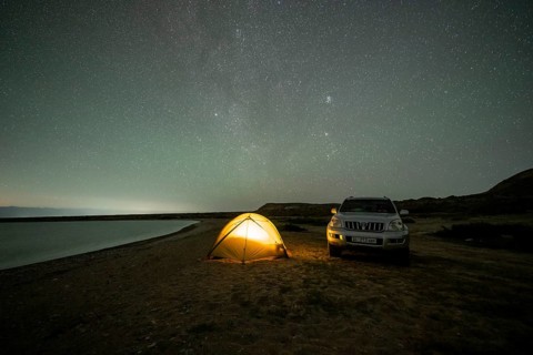 Off-road vehicle and tent, night shot, Milky Way at Lake Issyk Kul, Kyrgyzstan, Asia