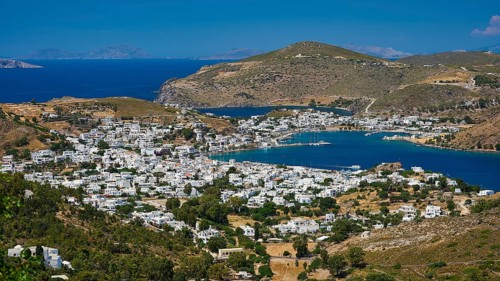 Picturesque coastal town with white houses and mountains in the background, surrounded by blue sea