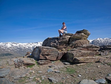 Woman sitting on rocky outcrop in the Sierra Nevada Mountains in the High Alpujarras, near