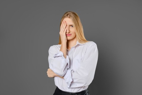 Portrait of a tired and frown young woman covering one eye with her palm