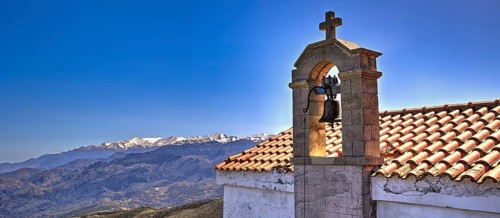Bell tower of a church in front of a mountain panorama on a sunny day, Chapel of Agios Ioannis