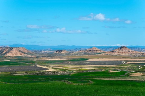 Vast landscape with rolling hills and green fields under a clear blue sky, Bardenas Reales Natural