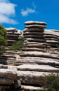 Round rock formations under a blue sky with scattered clouds and green vegetation, Karst Mountains,