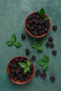 Two bowls, fresh, ripe blackberries, with leaves, top view, no people