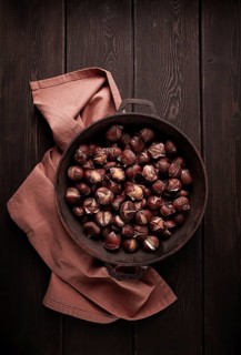 Roasted chestnuts, in an iron pan, wooden table, top view, no people, rustic style