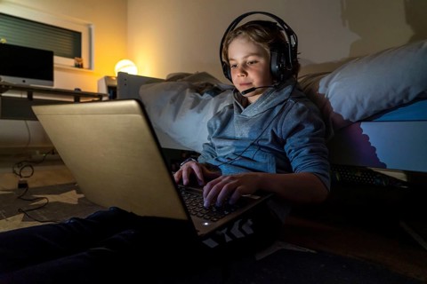 Boy, at home on the computer, laptop, in the children's room, playing a game, chatting with other