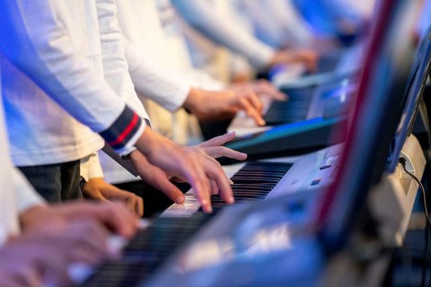 Young people, children play on many keyboards, simultaneously, electronic clarinet, at a concert