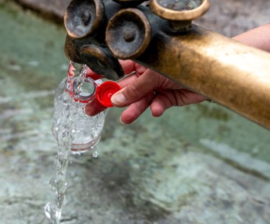 Water fountain, a woman fills drinking water into a small plastic bottle, Munich, Bavaria, Germany,