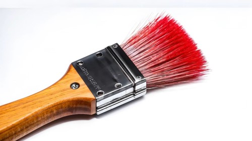 Thick paintbrush dipped in red bristles dripping onto a white background, AI generated