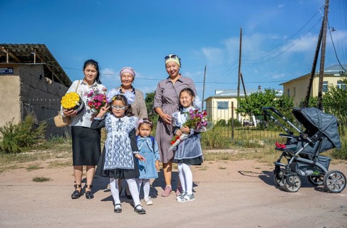 Family and schoolgirl with a bouquet of flowers on the first day of school, Issyk-Kul region,