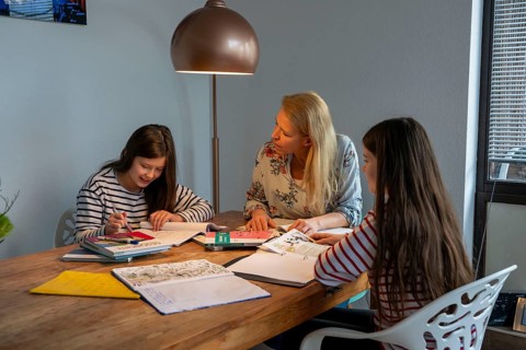 Homeschooling, during the lockdown in January 2021, mother helps her two daughters, at home,