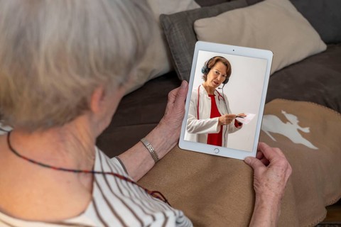Symbolic image of telemedicine, patient speaking to a doctor in a video conference from home