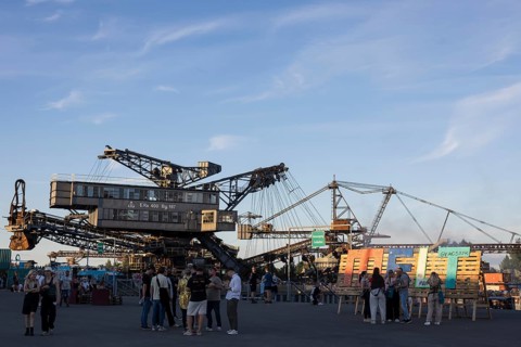 Festival visitors in front of open-cast mining excavator and Melt logo at the Melt Festival in