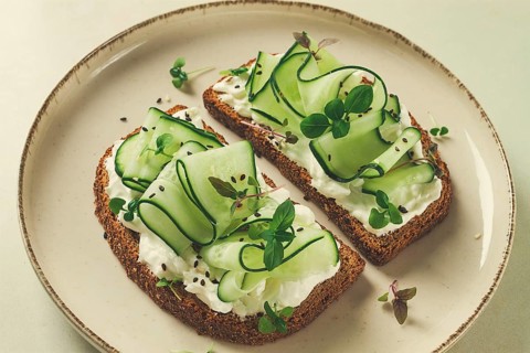 Breakfast, cereal bread sandwiches, cream cheese, sliced cucumber, with micro greenery on a light