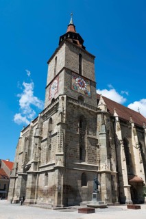Gothic church with tower under clear blue sky, large clock visible, Black Church, Old Town, Brasov,