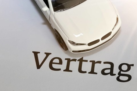 Symbolic image of car insurance: model car with contract documents