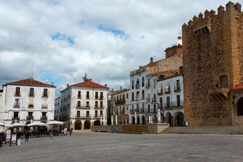 A large square with old buildings, a tower and cafés on the edge, tower, Torre de Bujaco on the