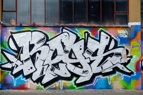 White and black graffiti with colourful accents in front of a window wall, Landau,