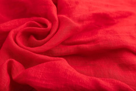 Fragment of red silk tissue. Side view, natural textile background and texture. wave concept,