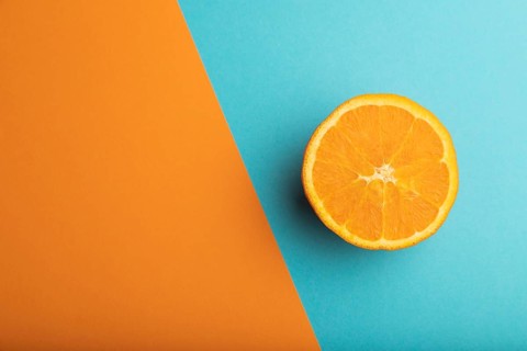 Ripe cut orange on orange and blue pastel background. Top view, flat lay, copy space. Tropical,