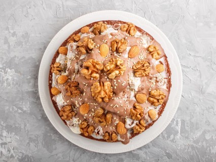 Homemade cake with milk cream, cocoa, almond, hazelnut on a gray concrete background with orange