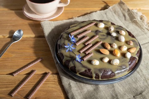Homemade chocolate brownie cake with caramel cream and almonds with cup of coffee on wooden