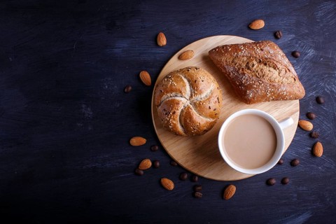 Cup of coffee with cream and buns on a black background. top view, flat lay, copy space